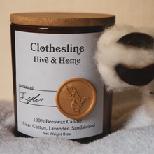 Load image into Gallery viewer, Our apothecary beeswax candle sits on a freshly washed and folded towel, and a bud of cotton perches on the right side of the screen in the foreground.