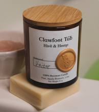 Load image into Gallery viewer, Our apothecary beeswax candle sits on a bar of natural coconut soap, on the side of a tub. Behind it is a small bowl with a pink grapefruit sugar body scrub. The bathwater is a bright green from a bath bomb.