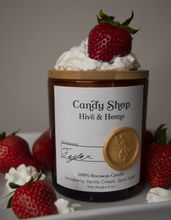Load image into Gallery viewer, Our apothecary beeswax candle sitting upright on a white plate. Fresh red strawberries and extra creamy whipped cream surround the jar.