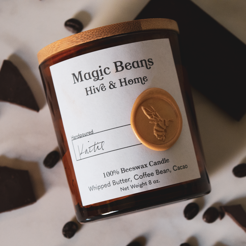 Flat lay of our apothecary beeswax candle against a marble background. Coffee beans and chunks of dark chocolate surround the candle.