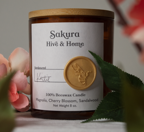 Cherry blossom branches in full bloom surround our apothecary beeswax candle, framing it in a resplendent moment